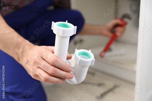 Photos Plumber with siphon working indoors, closeup. Space for text