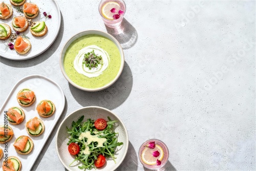 Ramadan food flat lay with copy space showcasing appetizers, creamy yellow soup, pink beverage glasses, and herb-garnished sauces on a marble-like gray tabletop, top-down view