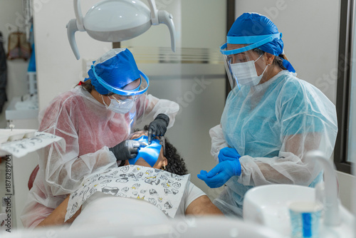 Horizontal shot of a dentist and assistant performing a dental procedure with UV light