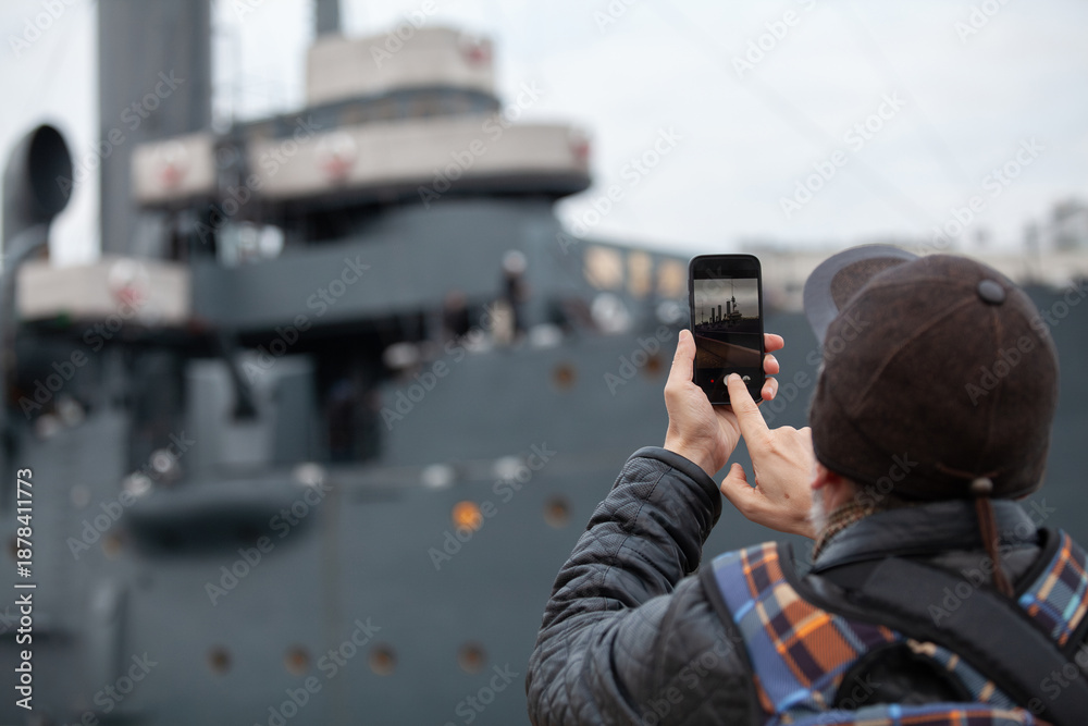 Fototapeta premium tourist takes smartphone photo of historic revolutionary warship