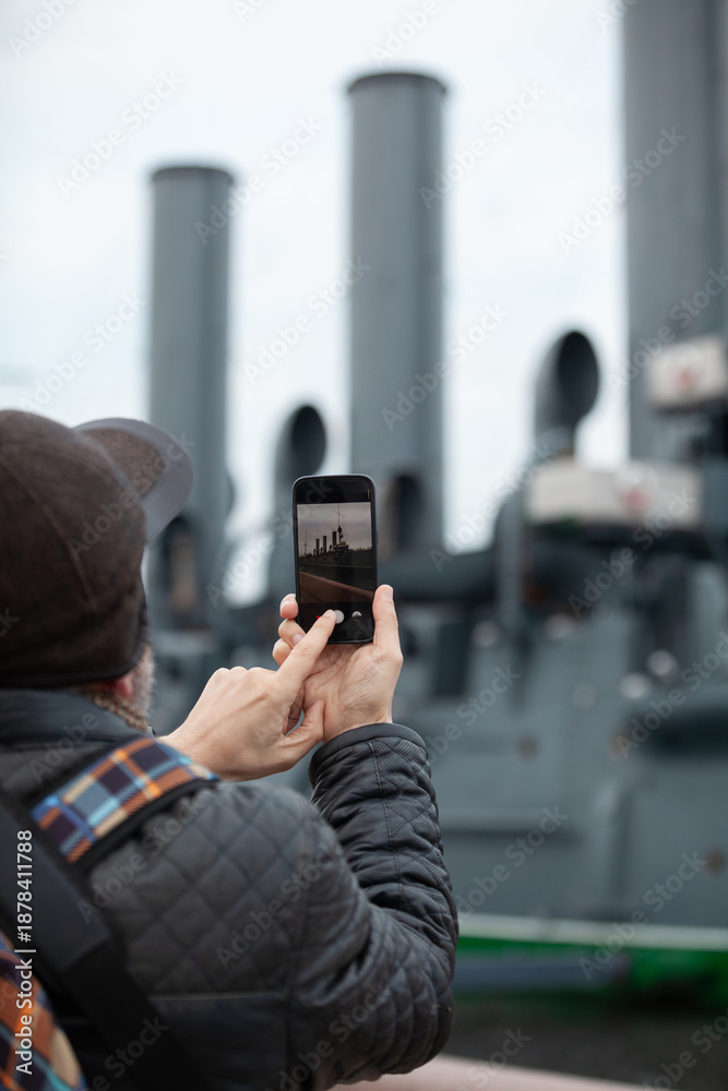 Fototapeta premium tourist takes smartphone photo of historic revolutionary warship