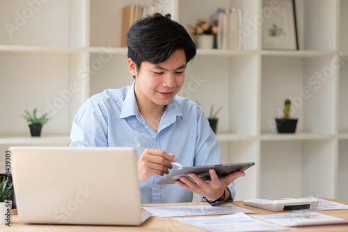 Foto Young accountant working with digital tablet and laptop at desk, reviewing financial documents