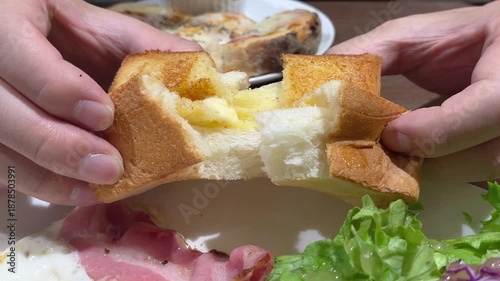 朝食のトーストした食パンを半分にちぎって食べる動画。