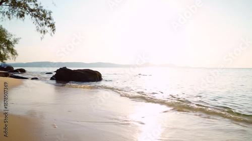 Waves at stone beach on sunset. Sunrise sea on shoreline. Beach pebbles. Trees on sea beach shore, splashing waves. Wild Shore landscape. Ocean sunset shoreline scenic. Wild beach in jungle of Vietnam