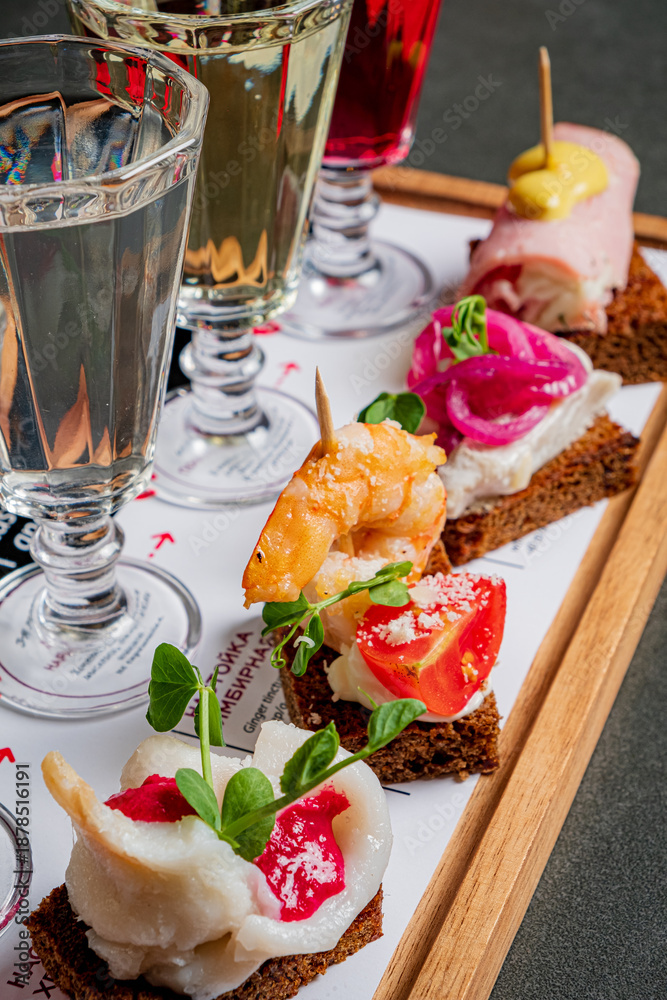 Obraz premium A colorful platter showcases various tapas paired with elegant drinks in a lively atmosphere
