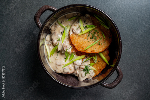 Foto Crispy pancakes sit in a bowl, lavishly covered with creamy mushroom sauce and g