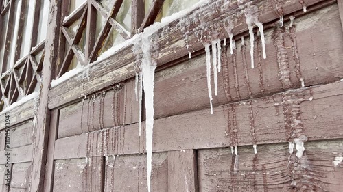Icicles in winter on an antique wooden window with patterns close-up as a background