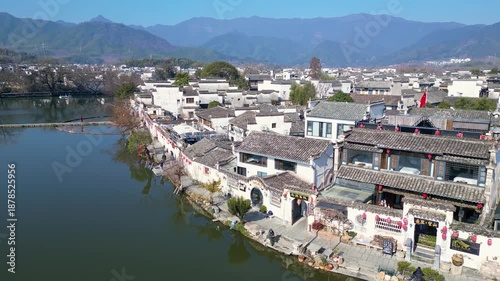 Hongcun, China: Aerial drone footage of the facade of traditional Hui ancient houses in Hongcun ancient village and temples by the pond in China. Shot with a forward motion.