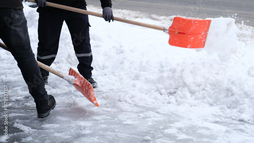Municipal workers are cleaning the sidewalks blocked by snow. snow removal workers with snow shovels