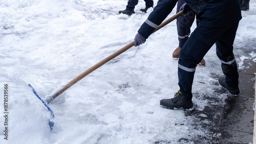 Municipal workers are cleaning the sidewalks blocked by snow. snow removal workers with snow shovels