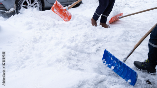 Municipal workers are cleaning the sidewalks blocked by snow. snow removal workers with snow shovels
