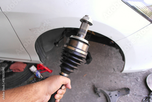 фотографія New CV Joint Installation, A mechanic holds a new CV axle joint with a protective rubber boot, ready for installation to fix car vibration and drive issues