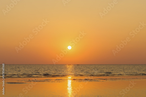 Glowing Sun Rising Over A Calm Sea In Warm Amber And Burnt Orange Tones.