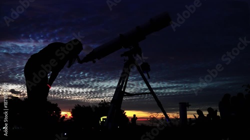Dark silhouette of an astronomical telescope and people exploring the night sky, symbolizing science, education, and mystery