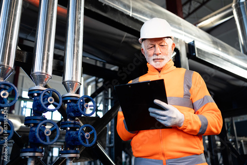 Senior engineer inspecting pipelines at an industrial plant