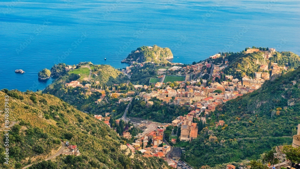 Obraz premium Castelmola, Italy - December 13, 2025: stunning panoramic view from Castelmola, Sicily, Italy. In the square below some people are walking and enjoying the tranquil atmosphere. Just before sunset.