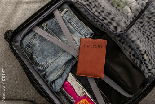 Billede på lærred Top-down view of open suitcase with folded jeans, passport, and organized compar