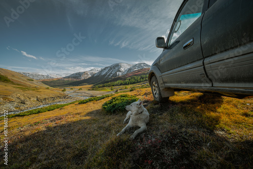 Foto An off-road vehicle with all-terrain tires is parked on a small autumn meadow overlooking a gorge and partially snow-dusted peaks