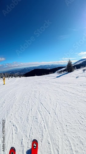 Travel and winter adventure concept. Beautiful POV ski landscape on the mountains. Skier skis down a snowy mountain trail in cloudy weather. Vertical shot in slow motion