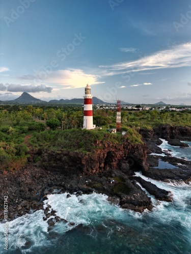 Drone view of Albion Lighthouse, Mauritius at sunset. Stunning coastal scene with golden light, ocean waves, and tropical landscape, perfect for travel and scenic footage.