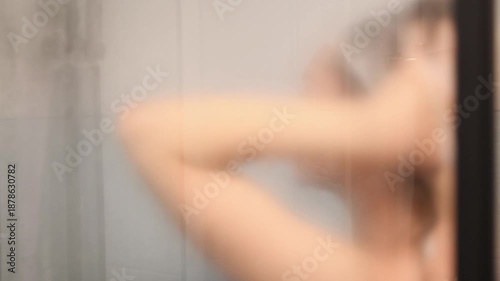 Blurred silhouette of woman in shower with soft lighting and steam