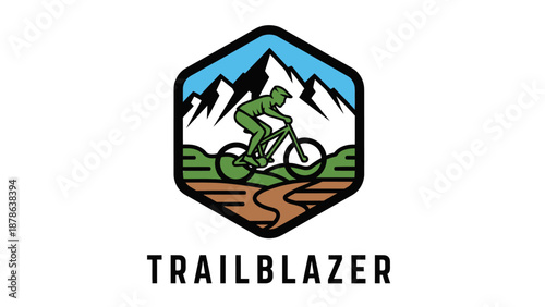 A hexagonal logo featuring a mountain biker on a winding trail with snow-capped mountains and a blue sky in the background, and green hills in the foreground, with "TRAILBLAZER" text below.