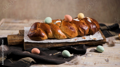 Foto Braided Easter Bread with Pastel Speckled Eggs on Rustic Wooden Board