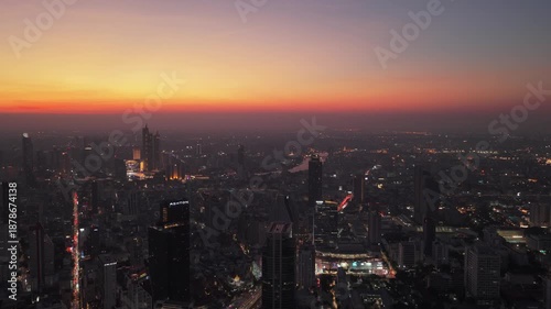 Wallpaper Mural Tripod aerial view of Bangkok's urban landscape at sunset. City lights illuminated buildings and streets below a colorful red sky Torontodigital.ca
