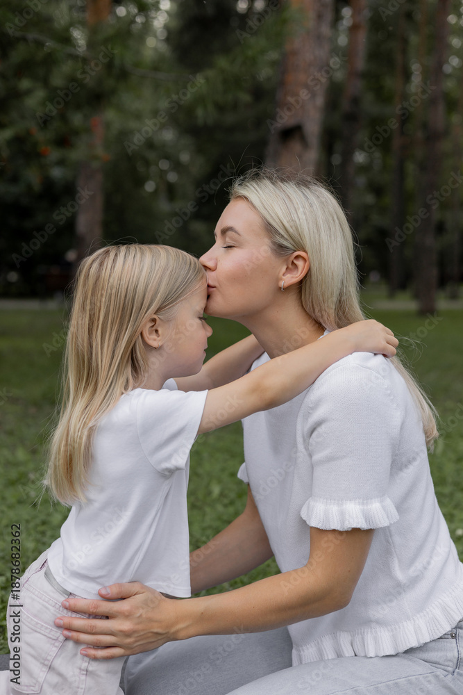 Fototapeta premium A mother hugs and kisses her child. A mother with a little daughter. The concept of maternal love, a vertical image.
