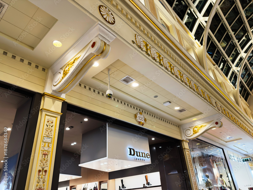 Obraz premium Ornate shopping arcade facade with gold detailing and modern Dune London storefronts in Manchester, UK