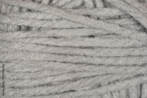 A macro shot shows the detailed texture of a soft grey wool yarn ball with thick intertwined threads filling the entire frame