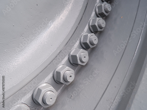 industrial heavy-duty wheel rim with large steel bolts and nuts. Grey painted metal flange for trucks or construction machinery detail
