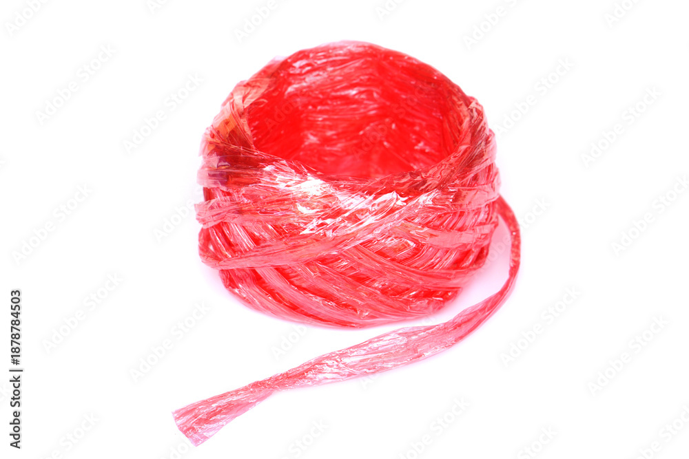 Obraz premium Red plastic rope or string roll isolated on white background. Concept of packaging material, household supply, recycling, waste management, tying, wrapping and everyday utility in minimal still life 
