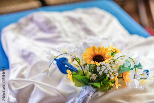 Closeup of a Yellow and Blue Floral Bouquet on a White Wedding Dress
