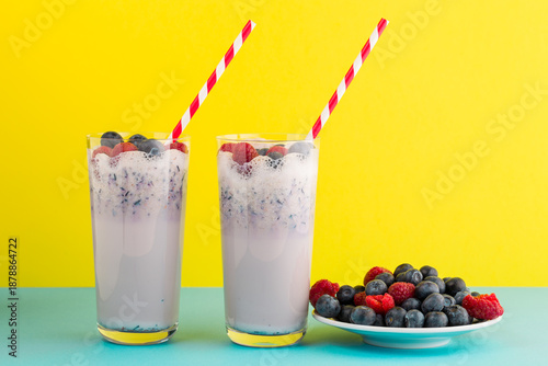Refreshing berry drinks in clear glasses on a bright background with berries on a plate nearby