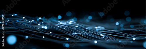 High speed fiber optic cable network for fast internet data transfer and digital communication technology background with glowing blue light particles and bokeh effects on black.