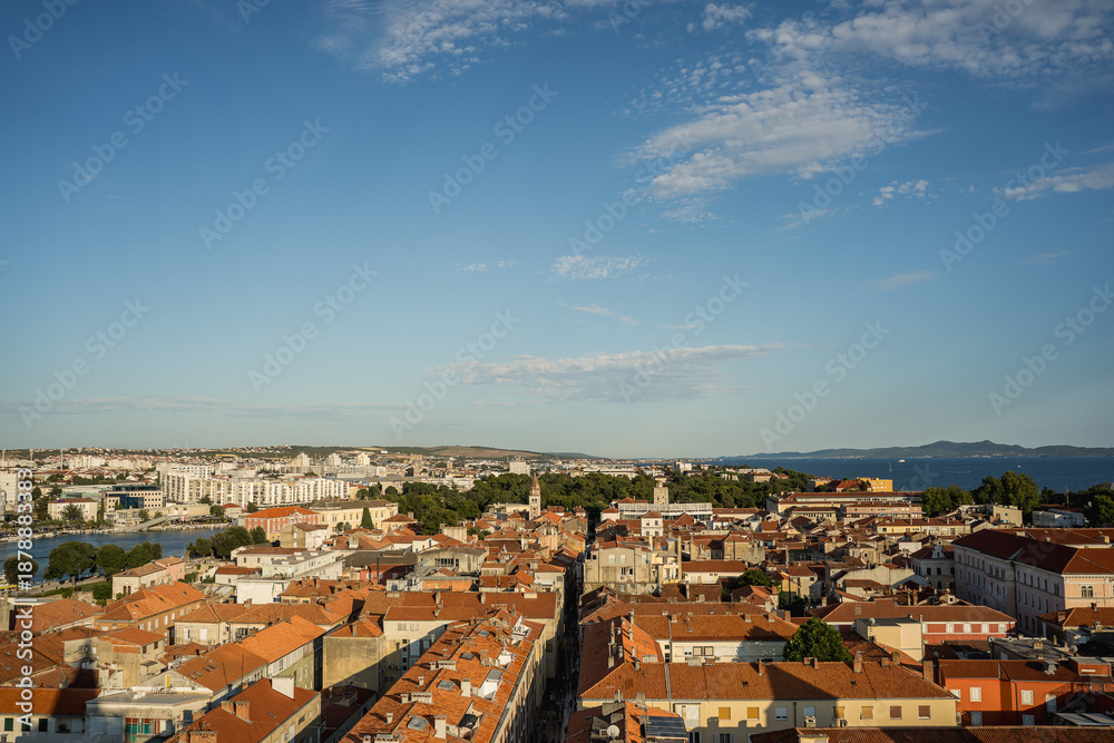 Fototapeta premium High viewpoint panoramic view of Zadar old town with red tiled roofs and Adriatic Sea seen from the bell tower. Travel destination cityscape with historic architecture and coastal horizon. 