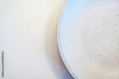Schilderij op canvas A top-down view of a modern white ceramic bowl with brown speckles, set against a clean off-white background