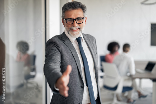 Φωτογραφία Experienced businessman extending hand for a shake in office