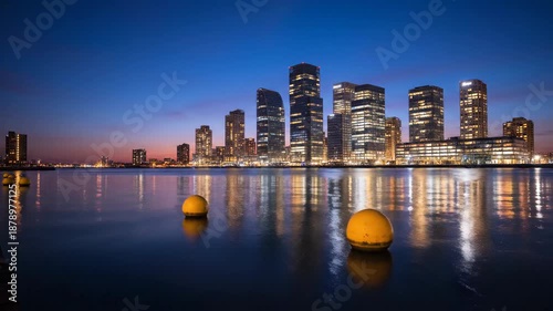 City skyline silhouette reflecting in water during dusk or dawn with colorful sky