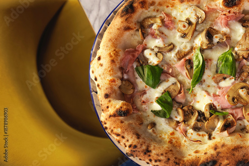 close up of a ham and mushroom pizza on marble tabletop border with visible seat