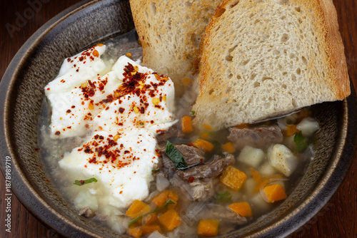 A bowl of delicious boiled beef broth with carrots and potatoes and yogurt