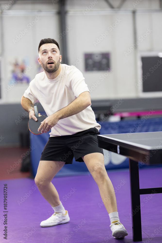 Fototapeta premium Young man playing table tennis during intense match
