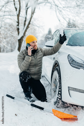 Man calling for assistance with electric car stuck in snow