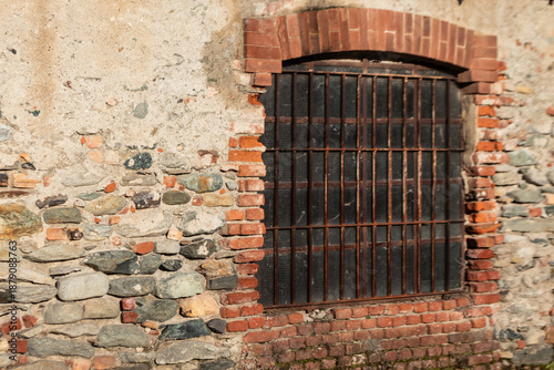 Cuadro en lienzo Old barred window set in a weathered brick and stone wall, perfect for architect