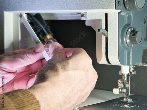 Canvastavla Close-up shot of a person's hand setting up or repairing an older, classic sewing machine