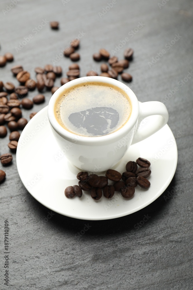 Obraz premium Refreshing coffee in cup and beans on dark textured table