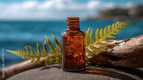 Amber glass bottle with fern by the sea on driftwood.