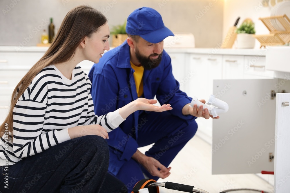 Fototapeta premium Young woman talking with plumber in kitchen