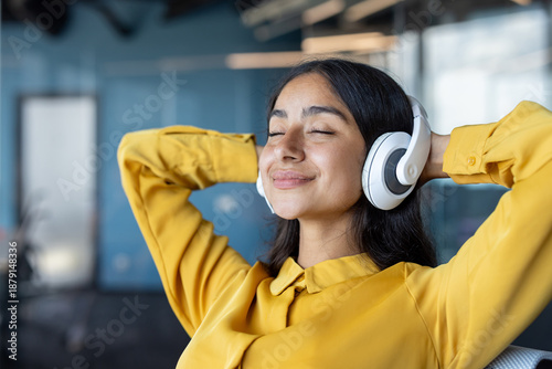 Photography Close-up photo of a young Indian woman wearing headphones sitting in an office c